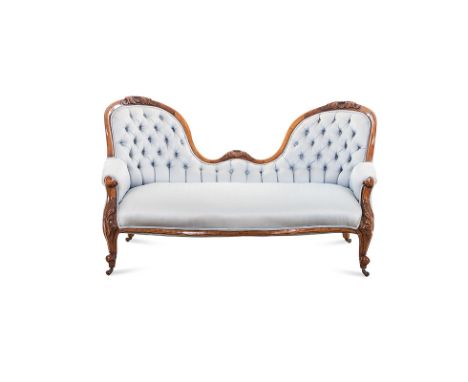 A VICTORIAN WALNUT SETTEE the curved top rail centred by a scrolled and foliate carved cresting, padded button back, padded a