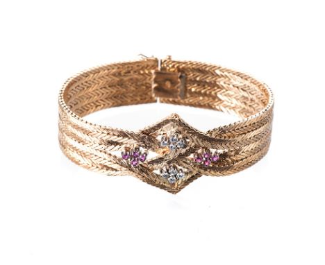 A RUBY AND DIAMOND BRACELET composed of eight strands of herringbone-link chain, plaited and crossed in the centre to form a 