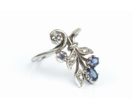 A SAPPHIRE AND DIAMOND PANEL RING, designed as a floral spray of oval and circular mixed-cut sapphires, with diamond set foli