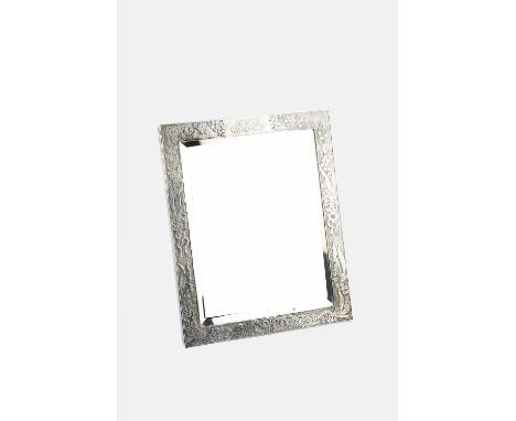 AN EARLY 20TH CENTURY AMERICAN SILVER FRAMED EASEL TABLE MIRROR, by Tiffany &amp; Co, the rectangular frame decorated with fl