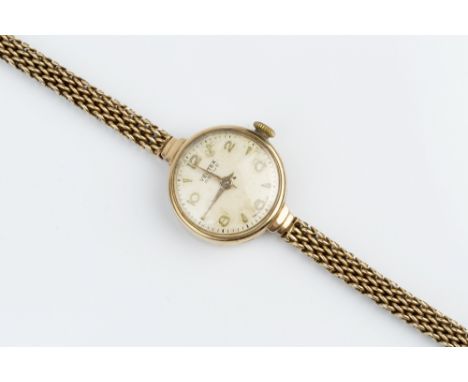 A LADY'S 9CT GOLD 'REVUE' BRACELET WATCH BY VERTEX, the circular silvered dial with alternated Arabic numerals and arrowhead 