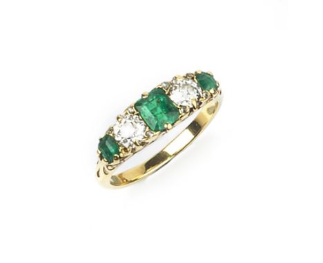 AN EMERALD AND DIAMOND FIVE STONE RING, the scroll decorated hoop set with graduated rectangular step-cut emeralds and old br