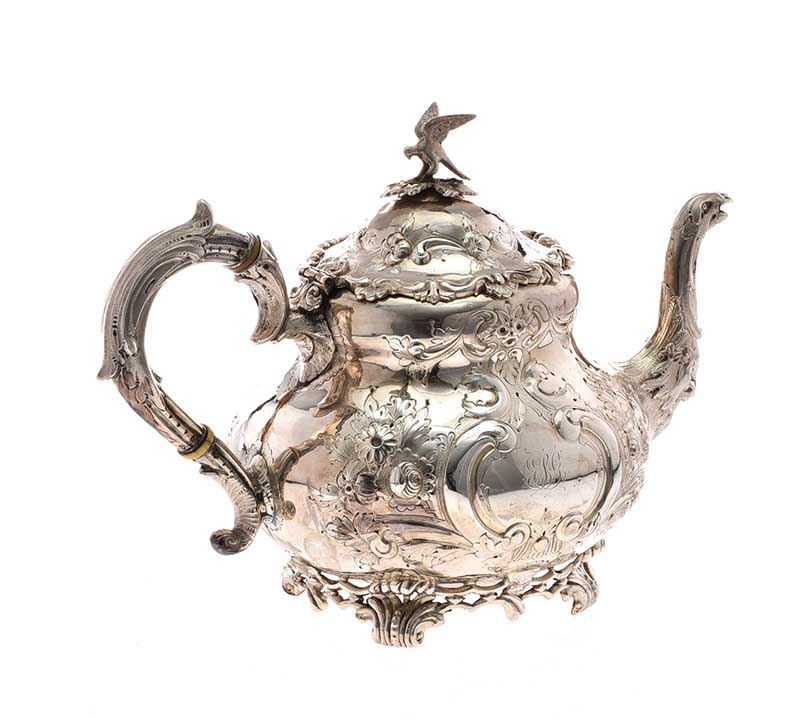 EMBOSSED IRISH SILVER TEA POT. DUBLIN 1890.MAKER WEST & SONS.RAISED ON A SHAPED FOOT BASE.INITIAL