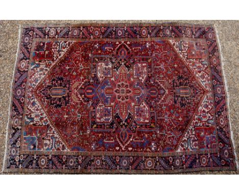 A Persian Heriz the centre worked with a large leaf and flower filled medallion on a red to rust ground the cream spandrels w