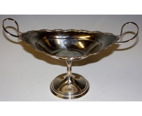 A two handled pedestal dish of shaped oval form, reeded borders and whip-lash handles, waisted column on circular foot, 25.5c