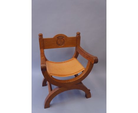 Robert Thompson Of Kilburn - an English oak X-frame chair the back with horizontal rail carved with the crest of The Hospital