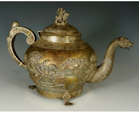 An Indian silver coloured metal teapot the hinged domed cover with deity riding a lion, the handle with mask and bust termina