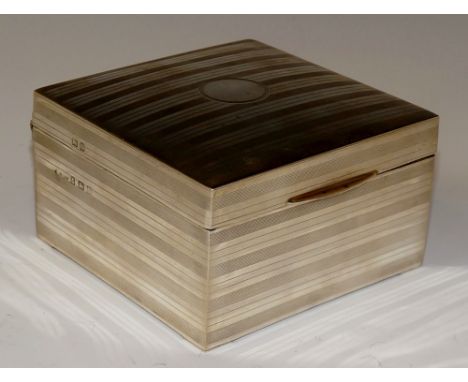 A square cigarette box and cover decorated overall with horizontal engine turned bands the hinged cover with vacant circular 