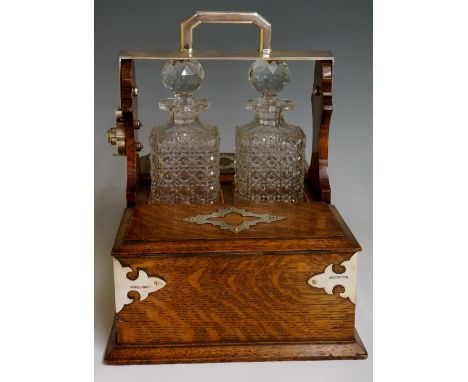A late Victorian silver mounted oak two bottle tantalus and games compendium, the handle with Bramah type lock with sprung le