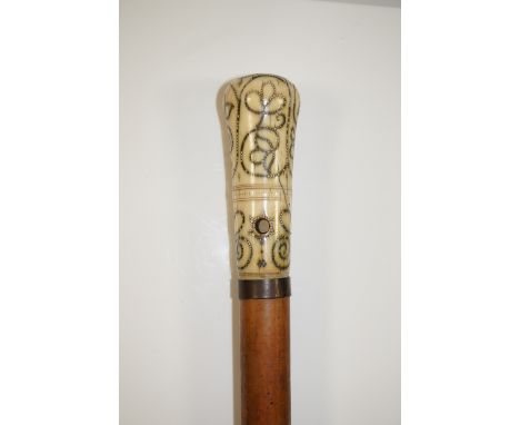 An 18th Century ivory handled piqué inlaid walking stick with stylised scrolling foliate decoration, the top with quatrefoil 