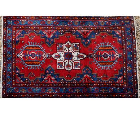 A Persian Karajeh worked with a central cream medallion flanked by two barbed medallions, spandrels and sides worked with par