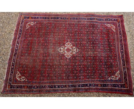 A Persian Bidjar carpet with central barbed cream medallion on a red ground filled with medallions, spandrels conforming, gua