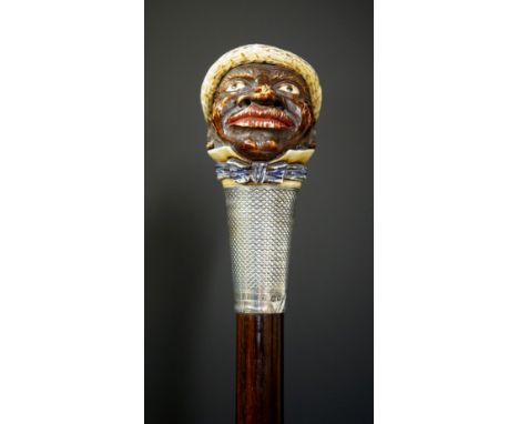 A walking stick with carved and stained ivory Blackamoor head wearing straw hat, blue bow tie, engine turned silver collar, b