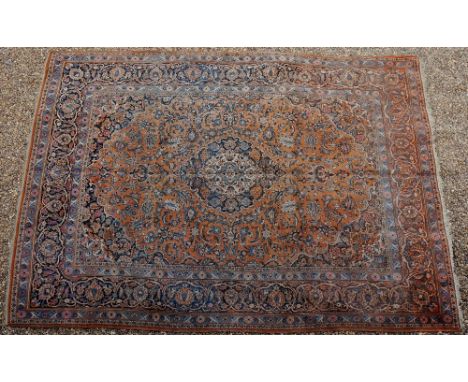 A Persian Kashan, the centre with floral blue and cream medallion on a rust coloured ground filled with conforming foliage, f
