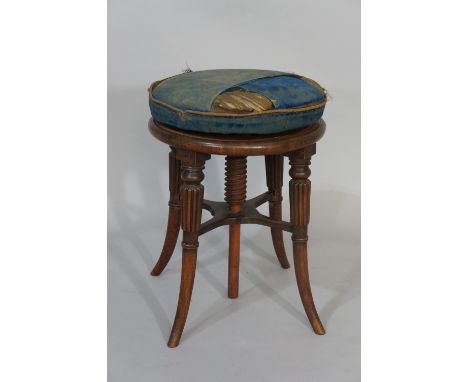 An early Victorian mahogany revolving piano stool the circular stuffed over top on a turned screw column, on fluted outswept 