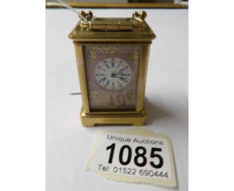 A brass cased miniature carriage clock with porcelain panels.