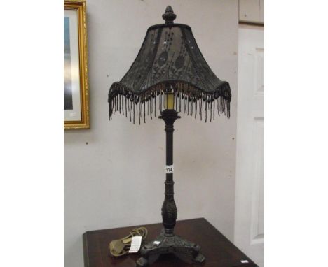 An ornate black table lamp with beaded shade