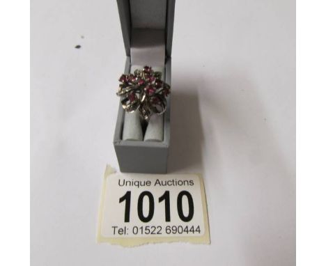 A circa 1970's ruby set cluster ring in whit metal in a floral design, size L.