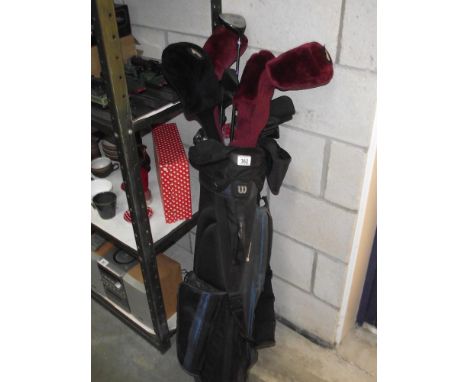 A caddy bag with golf clubs including Wilson