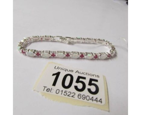 A silver opal and ruby line bracelet.