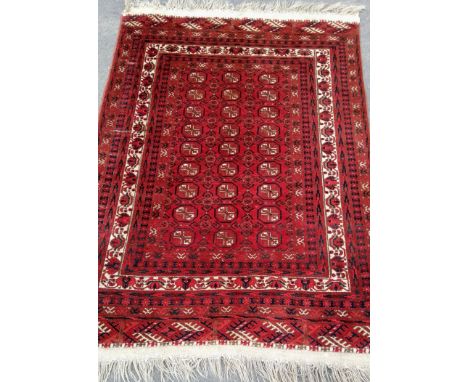 An Oriental burgundy-ground hand-knotted bokhara rug with double border and long fringe, 210 x 132 cm in good condition, ligh
