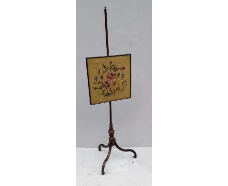 An early 19th century mahogany-framed pole screen with pineapple finial, embroidered screen on a tripod base 