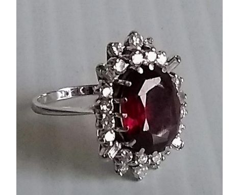 A garnet and diamond cluster ring in a claw setting, stamped 18ct, oval garnet 13mm x 10mm approximately, size K, 6.74g 