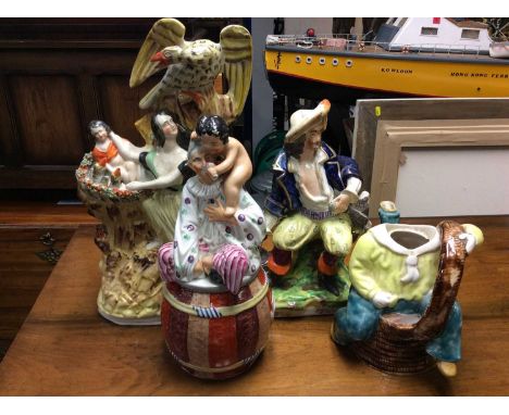 Staffordshire figure groups, tobacco jar in the form of a barrel with boy feeding a man, together with a majolica figure teap