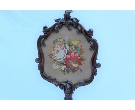 A William IV rosewood pole screen, with a carved floral framed, embroidered panel, a leaf carved column, on a pierced tripod 