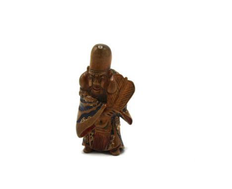 A 19th century Japanese wooden netsuke of Hotei standing holding a fan with red and blue lacquer detail, 5.2cm high 
