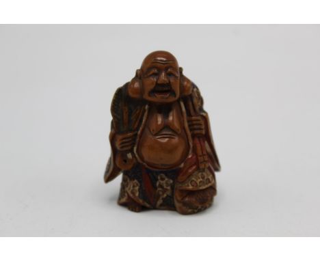 A 19th century Japanese wooden netsuke of Fukurokuju, shoen standing and holding a fan, with red and blue lacquer detail, sig