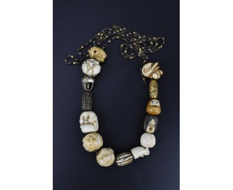 A 19th century Japanese ojime bead necklace, with carved ivory, bone, and metal ojimes, modelled as animals, masks, vegetatio