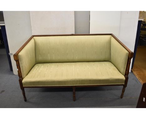 An early 19th century mahogany framed sofa with a moulded crest and arms, with turned supports, upholstered in a green watere