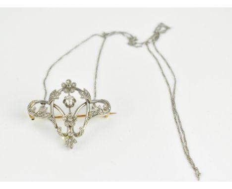 An Art Nouveau white and yellow gold wire framed brooch, fashioned as flowers and scrolled foliage, set with diamonds and a n