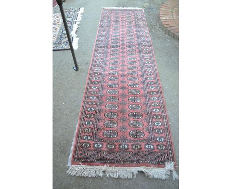 Pakistan runner of Bokhara design with two rows of gols on a pink ground, 10ft x 2ft 10ins approximately 