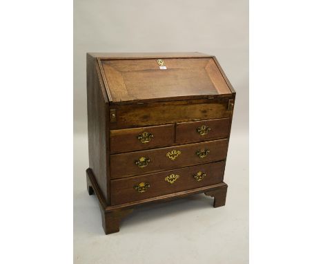 18th Century oak bureau, the fall front enclosing a fitted interior with well above two short and two long drawers with brass