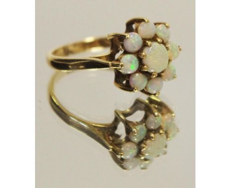 A 9ct gold opal flower head cluster ring central cabochon opal surrounded by eight smaller panels, 9ct gold shank 