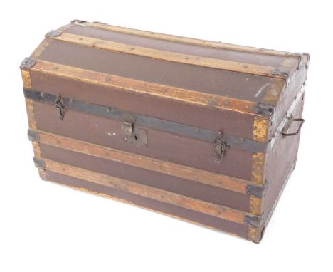 An early 20thC domed top travel trunk, with wooden strap work, and decorative paper lined interior, 49cm high, 77cm wide, 42c