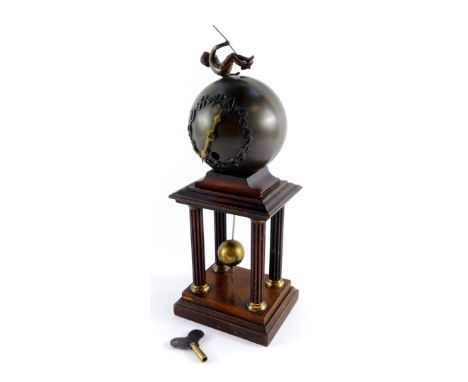 A late 19thC Junghans spelter and brass portico clock, formed as an orb with putto figure and drop pendulum on column base, t