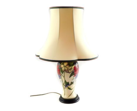 A Moorcroft pottery table lamp, of baluster form, decorated with mixed flowers against a cream ground, with shade, 67cm high.