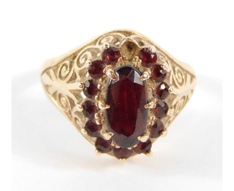 A 9ct gold garnet set dress ring, with layers of garnets on a raised basket with scroll design shoulders, Birmingham circa 19