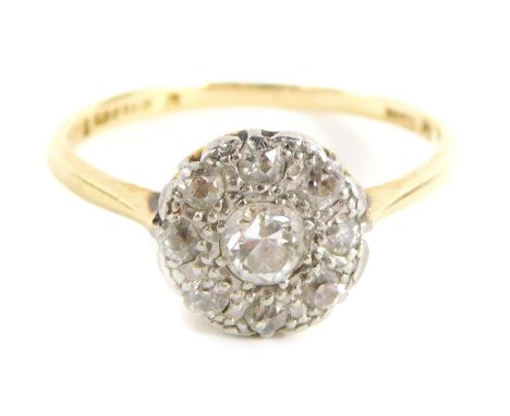 A diamond cluster ring, with central old cut diamond in a rub over setting with outer pave design of tiny diamonds, in a rais