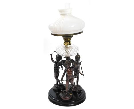 An early 20thC spelter oil lamp, cast as three standing cherubs with ribbons around a central spiral fluted column, raised on