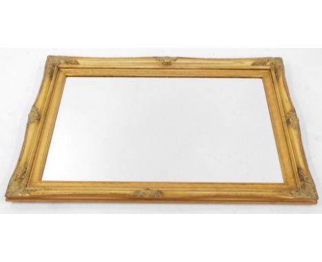 A Victorian style gilt framed rectangular wall mirror, with floral scroll capped detailing and arch top, on a bevelled mirror