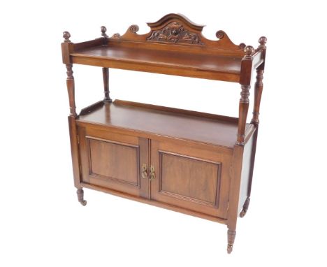 A Victorian mahogany buffet, the carved shield backed shelf top above a shelf topped pair of panelled doors, united by turned