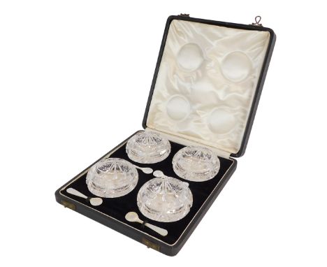 A set of four early 20thC cut glass circular salts, with mother of pearl spoons, cased. 