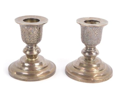 A pair of Thai silver squat pricket candlesticks, the tops with trailing leaf design, on stepped loaded bases, stamped Thaila