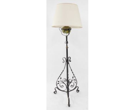 An early 20thC wrought iron oil lamp stand, converted to electricity, with brass reservoir, and cream shade, 162cm high, 51cm