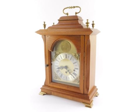 A mahogany cased mantel clock, with arched brass dial, silvered chapter ring with Roman numerals and brass spandrels formed a