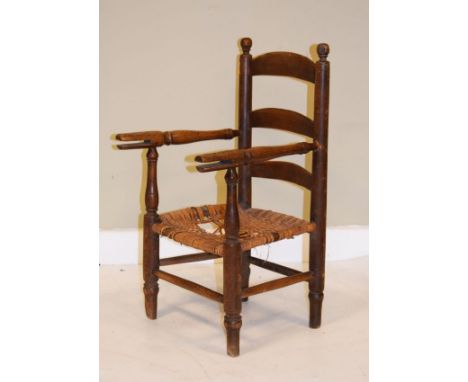 Victorian child's beech ladder back open arm chair having a rush seat and standing on turned supports   Condition: 